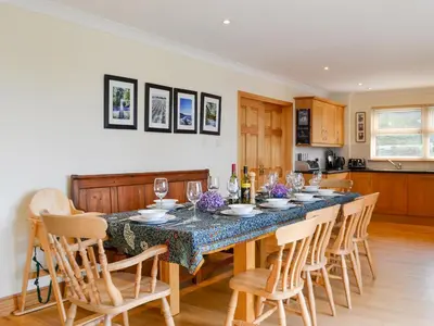 a dining room with a table with chairs and wine glasses at Saffron in Portpatrick