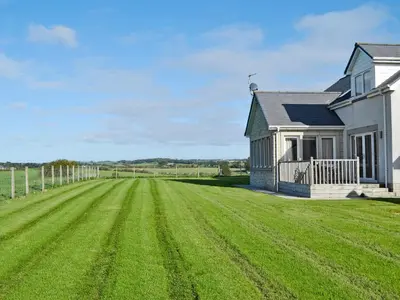a large grass field next to a house at Wheatfield House in Kilmaurs