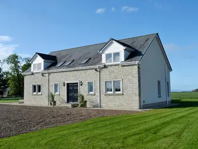 a large brick house with a green lawn at Wheatfield House in Kilmaurs