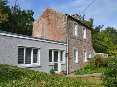 an old brick house with white windows and a yard at Blaithwaite Cottage in Blencogo