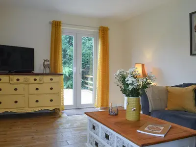 a living room with a couch and a table with flowers at Blaithwaite Cottage in Blencogo