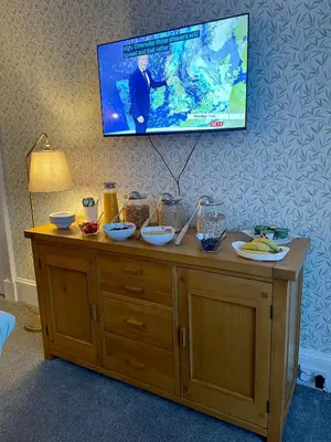a tv hanging above a wooden cabinet with food on it at Rockhill Guest House in Moffat