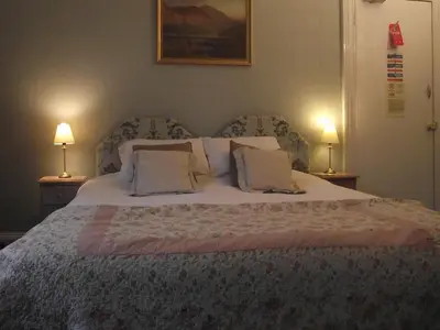 a bedroom with a large bed with two lamps at The Old Rectory in Annan