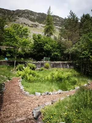 a path through a garden with a bench in the background at YHA Helvellyn in Glenridding