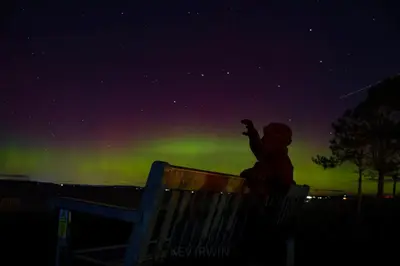 a person sitting on a bench looking up at the northern lights at Green View Guest House in Silloth