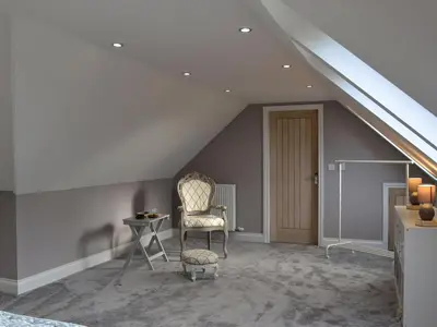 a room with a chair and a table and stairs at Torcross Barn in Tarbolton