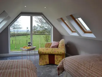 a bedroom with a chair and a large window at Torcross Barn in Tarbolton