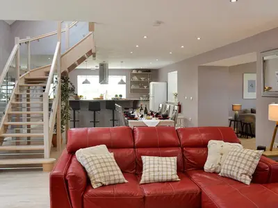 a red leather couch in a living room with a staircase at Torcross Barn in Tarbolton
