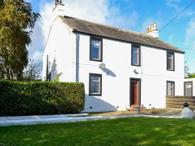 a white house with a hedge in front of it at Butterhole Farmhouse in Kelton
