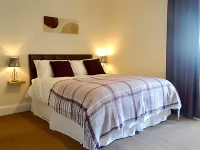 a bedroom with a bed with a blanket and two lamps at Butterhole Farmhouse in Kelton
