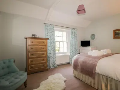 a bedroom with a bed and a dresser and a window at Stair Cottage in Keswick