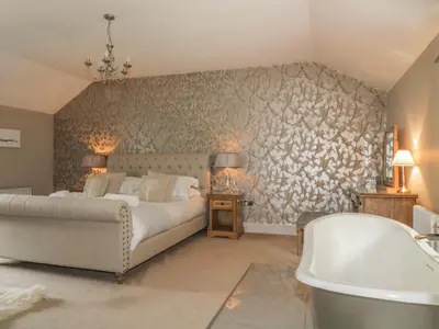 a bedroom with a bed and a tub and a sink at Stair Cottage in Keswick
