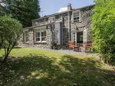 a stone cottage with a table and chairs on a lawn at Stair Cottage in Keswick