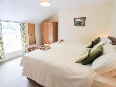 a bedroom with a large white bed with green pillows at Millcroft in Penrith