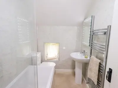 a white bathroom with a toilet and a sink at Millcroft in Penrith