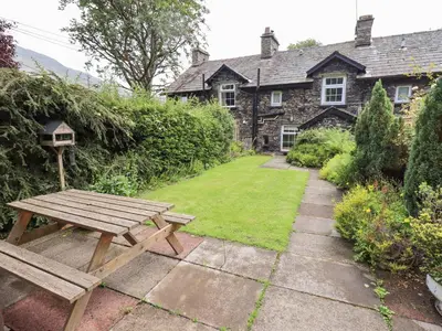 a wooden picnic table in front of a stone house at Millcroft in Penrith