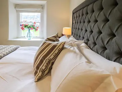 a bed with two pillows on it with a window at Beck Steps 1 in Grasmere