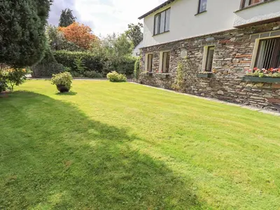 a large yard with a stone house and a lawn at Stonegarth Cottage in Ambleside