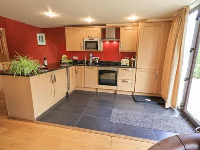 a kitchen with wooden cabinets and a red wall at Stonegarth Mews in Ambleside