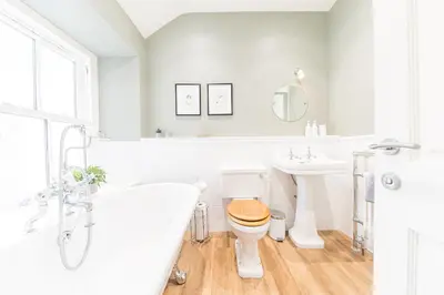 a white bathroom with a toilet and a tub and a sink at Poppy's Cottage in Ambleside