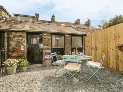a patio with a table and chairs in front of a building at Poppy's Cottage in Ambleside