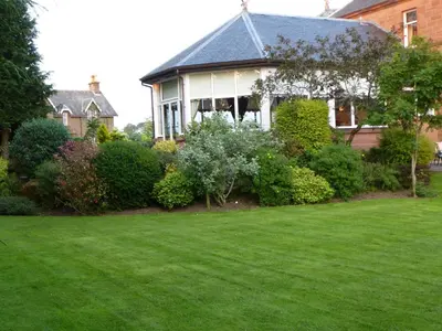a house with a green lawn in front of it at Somerton House Hotel in Lockerbie