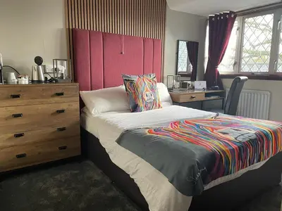 a bedroom with a bed with a dresser and a desk at Hunters Lodge Hotel in Gretna Green