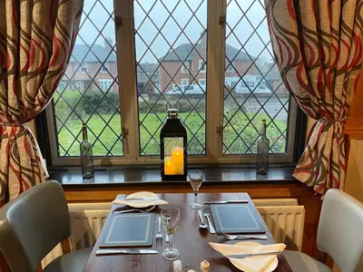 a table in a restaurant with a view of a window at Hunters Lodge Hotel in Gretna Green