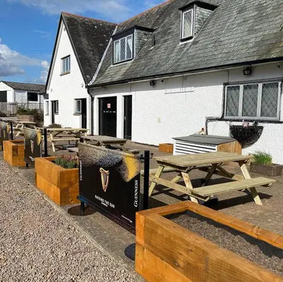 a group of picnic tables and benches in front of a building at Hunters Lodge Hotel in Gretna Green