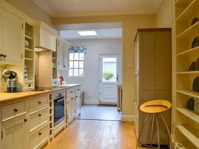 a kitchen with white cabinets and a wooden floor at Linton in Keswick