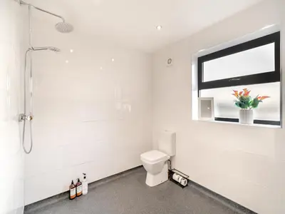 a white bathroom with a toilet and a window at North Plain Barn in Bowness-on-Solway