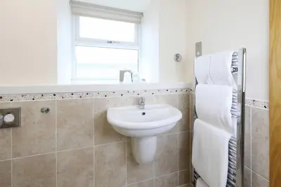 a bathroom with a white sink and a window at Woodland Bay Hotel in Girvan