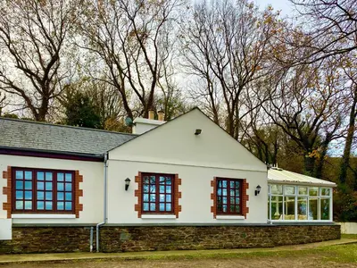 a white house with windows and trees in the background at Carrick Beg Self Catering Holiday Accommodation with Hot Tub in Sulby