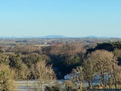 a view of a field with trees and a river at Carrick Beg Self Catering Holiday Accommodation with Hot Tub in Sulby