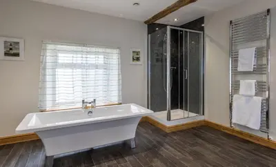 a white bathroom with a tub and a shower at The Inn at Ravenglass in Ravenglass