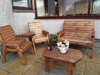 two wooden chairs and a table with a bottle of wine at Leafield Holiday Home in Stranraer