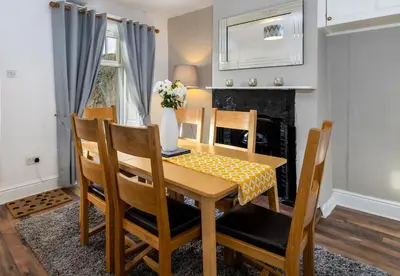 a dining room with a table and chairs and a fireplace at Muncaster Cottages in Ravenglass
