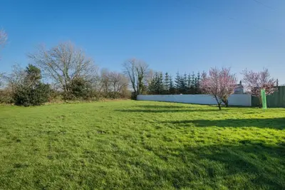 a large grass field with trees and a fence at Big White House in Cockermouth