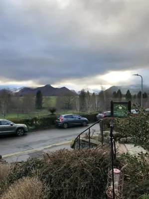 a group of cars parked on a road with a sign at Brundholme in Keswick