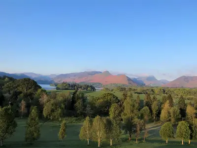an aerial view of a field with trees and mountains at Brundholme in Keswick