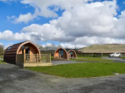 a couple of small wooden buildings in a parking lot at Withy Bottom-Uk1393 in Corney