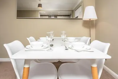 a white dining table with white chairs and a lamp at Cairn Suite - Donnini Apartments in Ayr