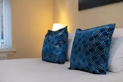 two blue pillows sitting on top of a bed at Cairn Suite - Donnini Apartments in Ayr
