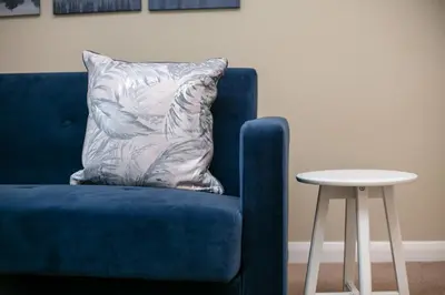 a blue chair with a pillow next to a table at Cairn Suite - Donnini Apartments in Ayr