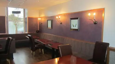 a dining room with tables and chairs and a wall at Royal Hotel in Girvan