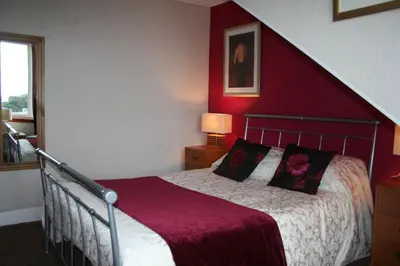 a bedroom with a bed with a red wall at Royal Hotel in Girvan