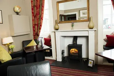 a living room with a fireplace and a mirror at Eskdale Hotel in Langholm