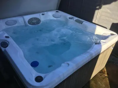 a jacuzzi tub with blue water in it at Sunset Retreat Lodge with Hot Tub in Carsethorn