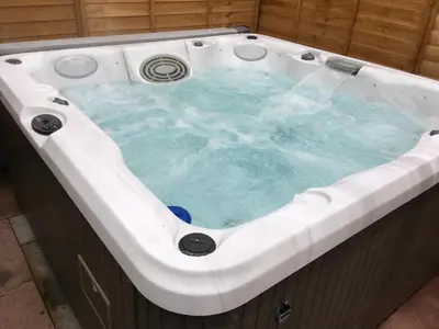 a jacuzzi bathtub with blue water in it at Sunset Retreat Lodge with Hot Tub in Carsethorn