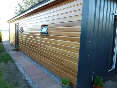 a wooden wall with a window on the side of a house at Sunset Retreat Lodge with Hot Tub in Carsethorn